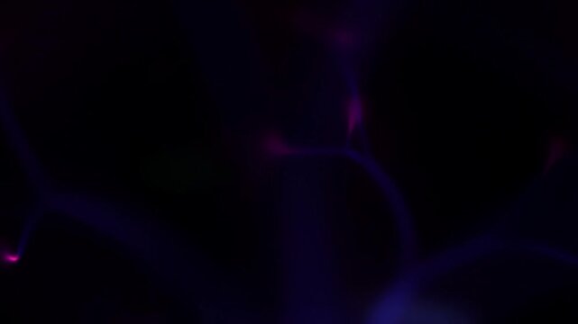 Cinematic soft focus purple and blue plasma energy filaments flickering gently in a dark environment creating a diffuse ethereal glowing background for science projects.