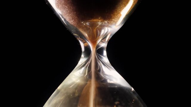 Close up view of sand flowing through hourglass on black background, indicating passing of time and urgency.