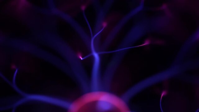 High angle view of a glowing pink electrode emitting multiple blue electric plasma arcs that fill the glass sphere with constant flickering energy.