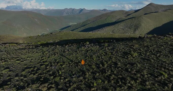 Aerial footage of woman trail runner cross country running on high altitude mountain top, slow motion