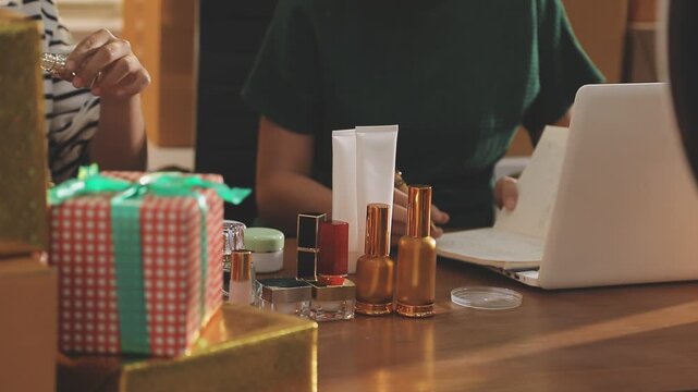 Young beautiful Asian girl reviewing cosmetic and skin care product with new collection's promotion selling on social media online live blurred phone screen surrounded beauty merchandise. Stratagem.