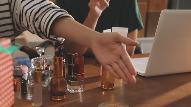 Young beautiful Asian girl reviewing cosmetic and skin care product with new collection's promotion selling on social media online live blurred phone screen surrounded beauty merchandise. Stratagem.