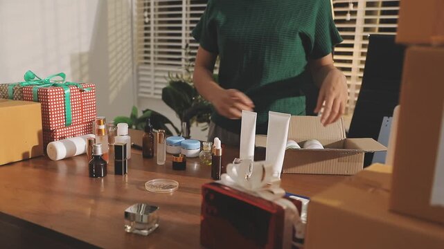 Young beautiful Asian girl reviewing cosmetic and skin care product with new collection's promotion selling on social media online live blurred phone screen surrounded beauty merchandise. Stratagem.