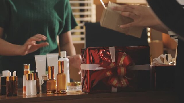 Young beautiful Asian girl reviewing cosmetic and skin care product with new collection's promotion selling on social media online live blurred phone screen surrounded beauty merchandise. Stratagem.