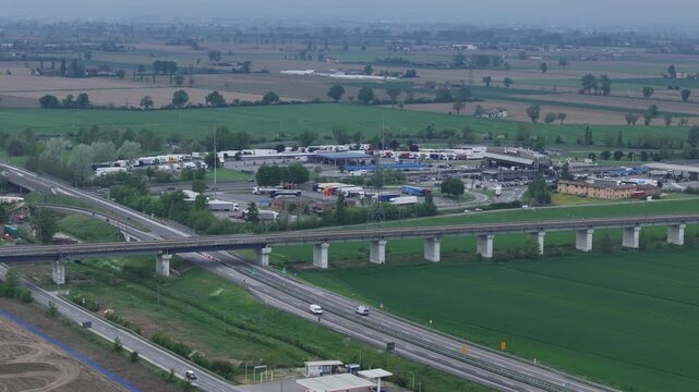 A1 A21 junction with SS9 Via Emilia and railway corridor near Piacenza Province Emilia Romagna Italy showing traffic flow, viaduct and farmland in Po Valley, drone static telephoto lens