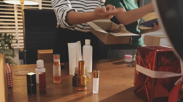 Young beautiful Asian girl reviewing cosmetic and skin care product with new collection's promotion selling on social media online live blurred phone screen surrounded beauty merchandise. Stratagem.