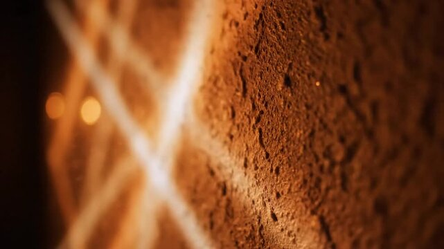 Close up view of rough textured wall with light reflecting abstract diamond pattern creating warm atmospheric ambience