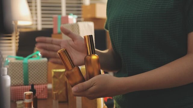 Young beautiful Asian girl reviewing cosmetic and skin care product with new collection's promotion selling on social media online live blurred phone screen surrounded beauty merchandise. Stratagem.