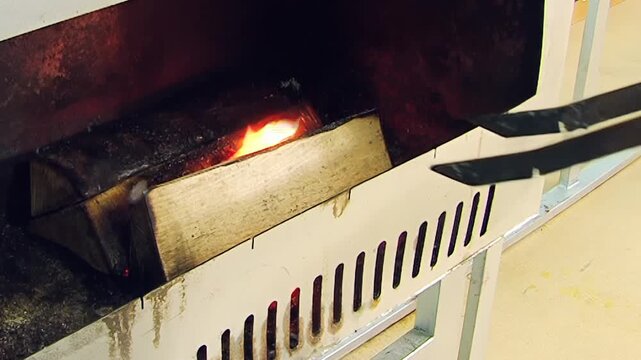 Captivating view of wood transforming into fire. Inside a rugged metal furnace, dry logs are coaxed into a vibrant, glowing blaze.