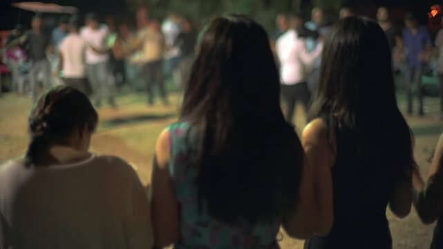 Kurdish women perform halay dance at traditional wedding with drums, rhythm cultural celebration. Female line movement shows regional folk heritage, communal joy scene festive outdoor ceremony.