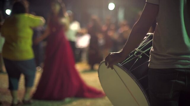 Woman in red dress dances at rural wedding with halay circle, drums night celebration. Open air festive movement unfolds around folk music, cultural scene joyful community ritual.