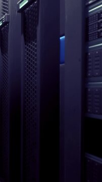 Rows of server racks fit closely in a data center. Green lights indicate active servers. The space is filled with technology equipment used for data storage and processing.