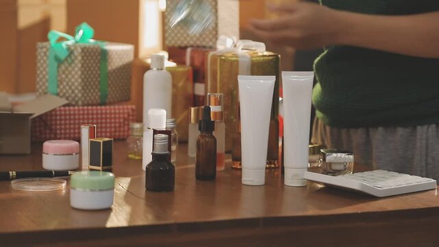 Young beautiful Asian girl reviewing cosmetic and skin care product with new collection's promotion selling on social media online live blurred phone screen surrounded beauty merchandise. Stratagem.