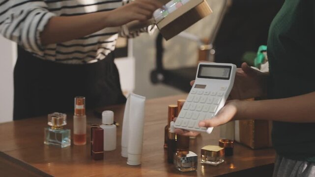 Young beautiful Asian girl reviewing cosmetic and skin care product with new collection's promotion selling on social media online live blurred phone screen surrounded beauty merchandise. Stratagem.