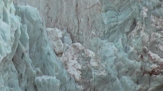 A colossal Arctic glacier undergoes a dramatic transformation, its ancient, blue-hued ice fracturing and descending.