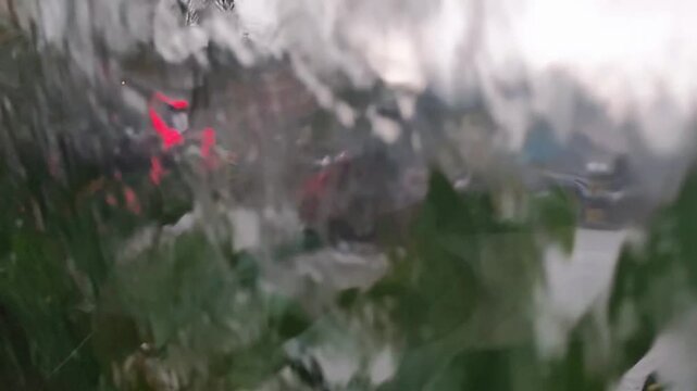 Raindrops streak across a glass surface
