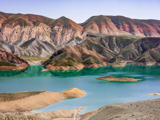 Obraz premium Colorful mountainous landscape with calm turquoise lake and sandy shores