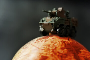 Naklejka premium Miniature armored military vehicle positioned on a firely globe representing modern warfare, geopolitical instability, defense strategy, international conflict, and rising global security concerns.
