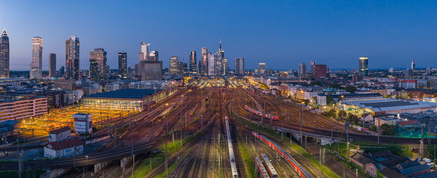 Aerial view of the Hauptbahnhof railway tracks and the illuminated skyscraper skyline during twilight in Frankfurt am Main, Hessen, Germany.