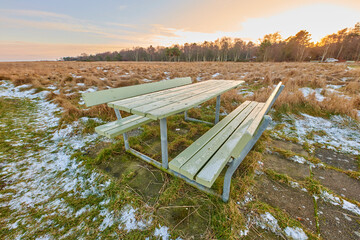 Naklejka premium Landscape, sunset and winter with bench in park for sustainable environment and cold meadow. Natural ecology, snow and wilderness with conservation, countryside and field scenery of reservation
