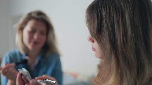 Mother teaching teenage daughter how to apply makeup