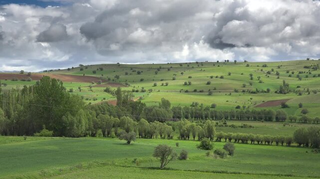 Green farmland fertile meadows Germany across rolling hills fields rural terrain detail. Cultivated countryside shows orchards grassland patchwork plots cloud covered relief.