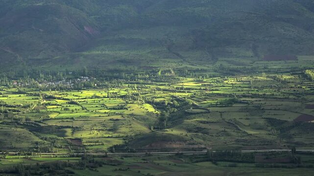 Green farmland fertile meadows Ethiopia across rolling hills fields rural terrain detail. Cultivated countryside shows orchards grassland patchwork plots cloud covered relief.