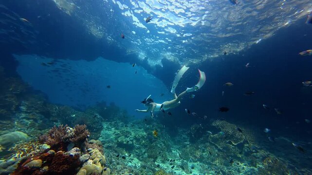 Young woman in swimsuit snorkeling in transparent tropical sea above coral reef,Summer travel concept	
