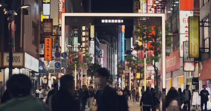 Ginza street in Tokyo city. Pedestrians walking through bustling commercial district street in night Japan. Surrounded by vibrant illuminated kanji signs. Dynamic urban scene. Luxury shopping travel