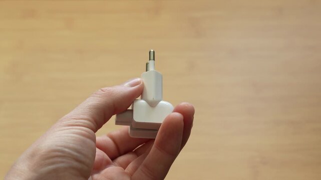Close up of male hands showing European electric plug from different angles. Concept of electricity, power connection, device compatibility and product demonstration.