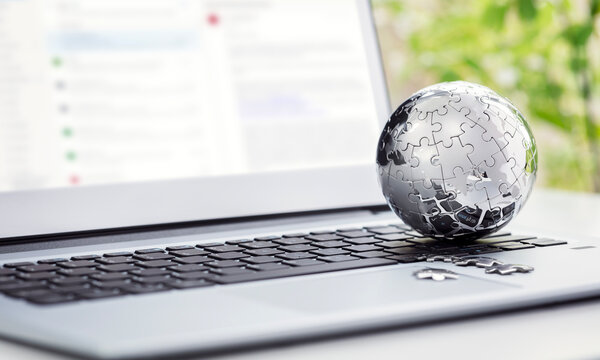 Chrome earth jigsaw puzzle on laptop keyboard concept for global strategy and communications