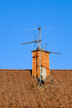 Alte Fernsehantenne mit Satellitensch&uuml;ssel an einem Schornstein auf einem Dach