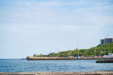 Fototapeta premium Scenic coastal view of a wooden pier and distant city under a bright sky