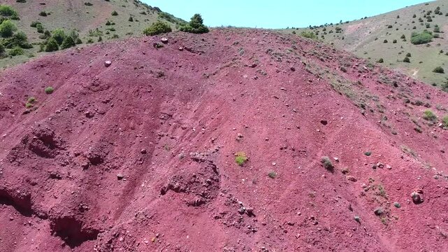 Exposed mineral outcrop reveals red strata and ore bearing layers across a barren slope. Mining geology and weathered bedrock create a survey scene with resource detail and rough terrain.