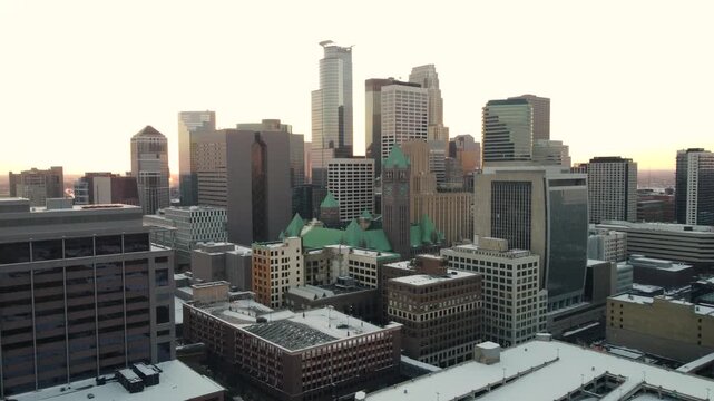 Aerial view of downtown Minneapolis city skyline during winter sunrise with snow covered rooftops.