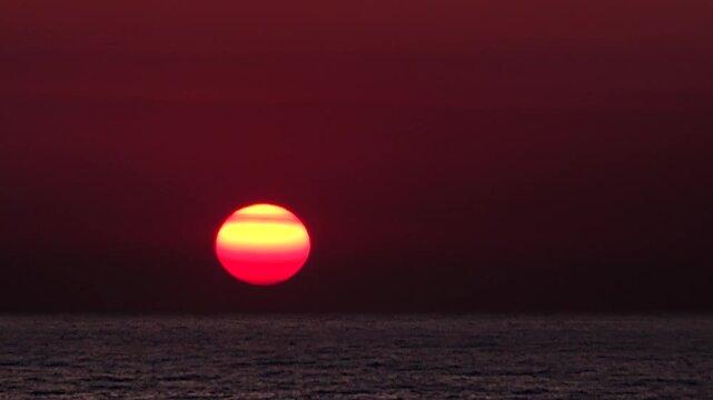 Sunrise colors the sea with orange and blue, spreading soft light across calm open water. Dawn sky and marine horizon create a peaceful seascape with gentle gradients and early glow.