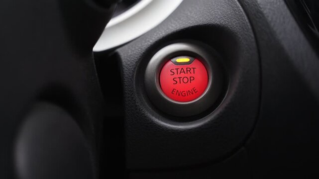 a glowing red start stop engine button on a modern car dashboard. High-contrast interior shot highlighting automotive technology and ignition systems.