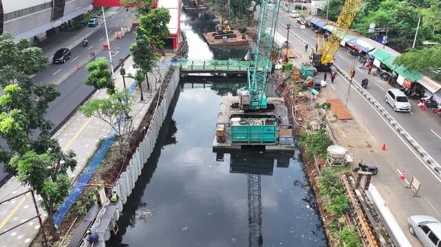 Sustainable Urban Planning for Future Cities Aerial view of bridge foundation construction on a river, featuring heavy steel sheet piling, concrete reinforcement, and a tall tower crane on a cofferdam