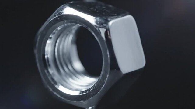 Close-up of a Shiny Hex Nut with Detailed Threading on a Dark Background