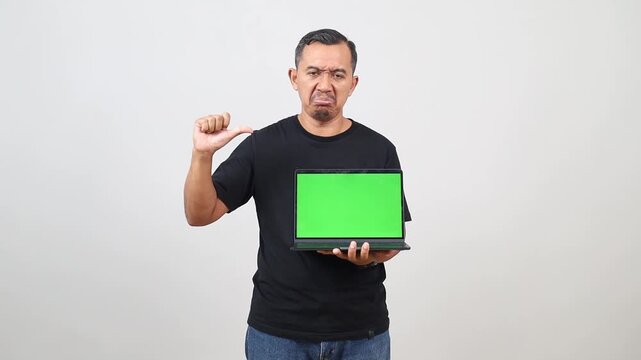 Asian man hold laptop pc computer, blank screen workspace area show thumb down gesture isolated on white background studio portrait.