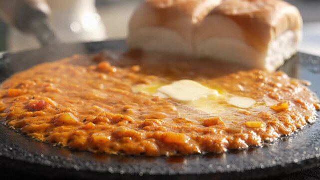 Hot pav bhaji simmering with melting butter and soft buns on a tawa, a vibrant indian street food.