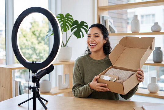 Smiling young woman recording an unboxing video with a ring light