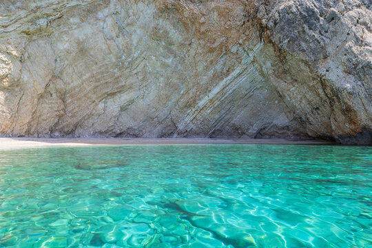 Clear turquoise blue water  and rock wall on small Kastelli beach on Corfu island.