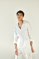Handsome young man dressed in white linen exudes confidence in bright studio space © LIGHTFIELD STUDIOS