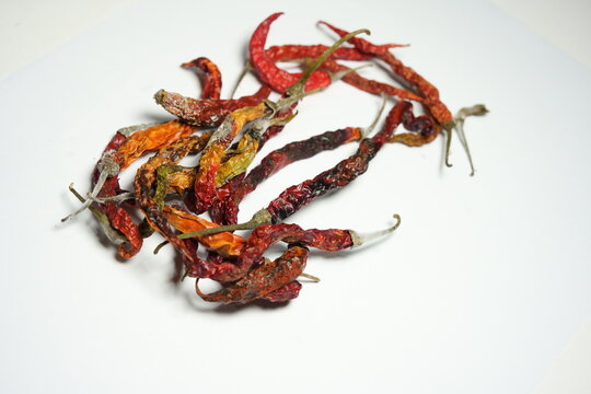Close up of moldy dried red chili peppers on white background. Rotten dehydrated chilies with visible white fungus and spoilage, isolated top view.