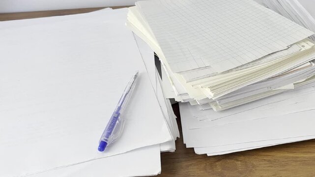 Video of scattered papers spread across a desk. Messy workspace scene representing stress, paperwork, office chaos, disorganization and busy work routine.