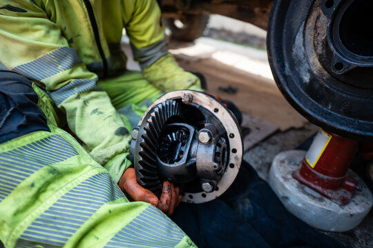 Mechanic holding differential gear during vehicle repair