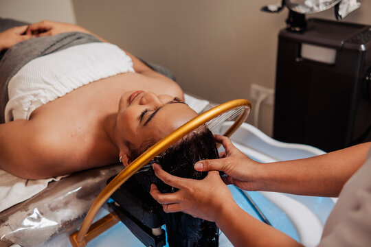 Young asian lady receiving aqua ring water halo scalp rinse at a Japanese head spa for scalp cleansing, relaxation, hydration, and soothing hair therapy.