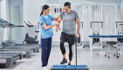 Fototapeta na wymiar Professional physiotherapist guiding a senior man through rehabilitation exercises on a step platform, representing strength, recovery, and expert care in a modern clinical fitness gym.