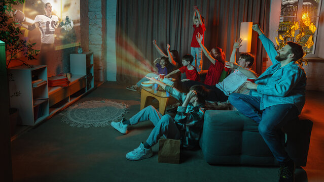 Big family watching American football projection at home with cheering children. Concept of live sports streaming, fan night, subscription media, home cinema, family fun, and weekend viewing.